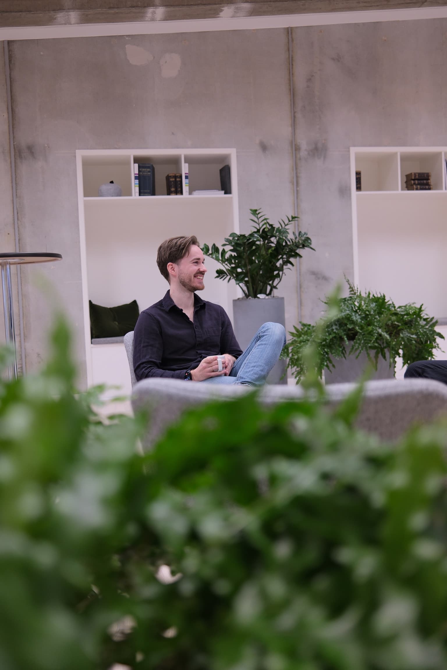 En fra Instans sidder med en kop kaffe i kontorets loungeområde